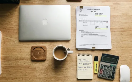 Healthcare billing desk with payment ledger, EOB documents, calculator, and highlighter pen.